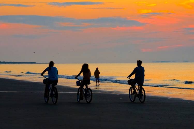 family riding beach cruisers on Hilton Head beach at sunset