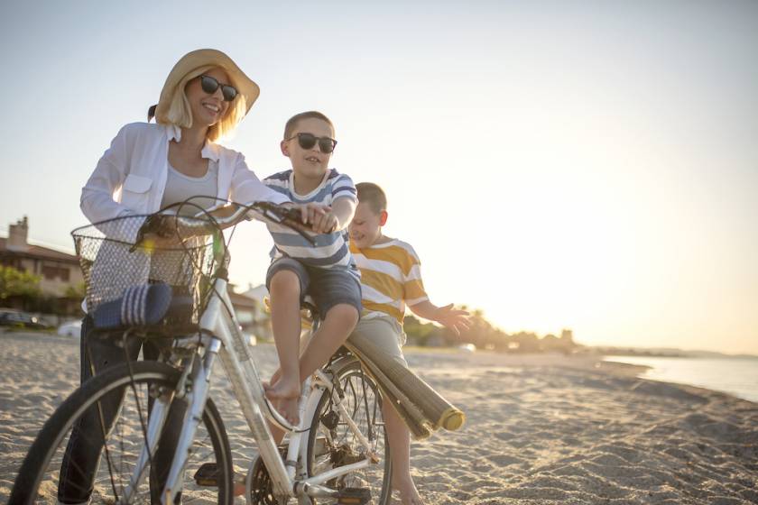 mom and kids on the beach riding bikes