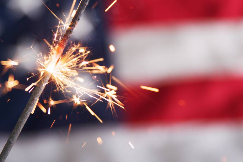 sparkler in front of blurry american flag
