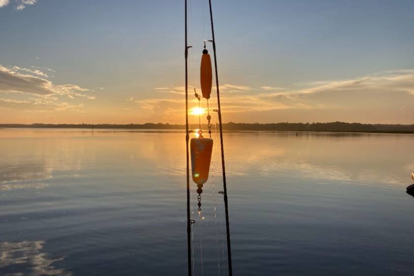 fishing pole with lures centered with sunrise over Hilton Head water in the background