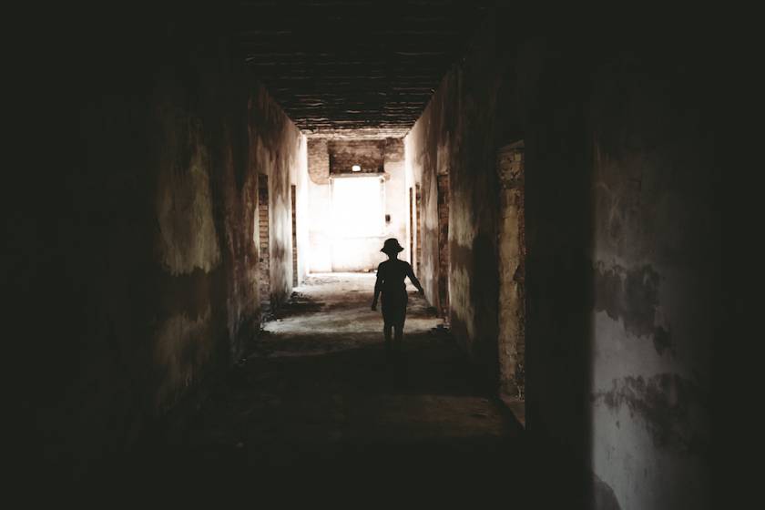 creepy shadow of a child at the end of a long, dirty hallway