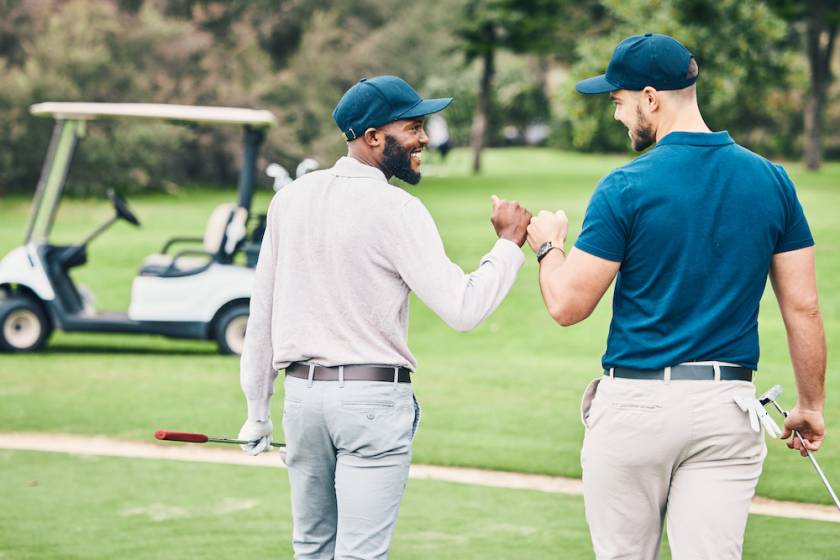 two men playing golf walking toward their cart