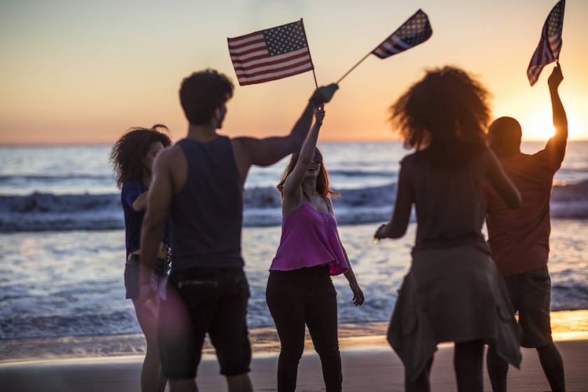 people waving flags on beach on 4th of july